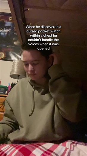 Part 2! VD: white boy called Jamie with dark brown hair tied up, sat on the bottom bunk of a bunk bed, wearing a green hoodie, there are two clips, in the first clip I pick up a golf pocket watch, open it, and start to look overwhelmed, covering my ears, shutting the pocket watch, and rocking back and forth, the text at the top of the screen says “When he discovered a cursed pocket watch within a chest he couldn’t handle the voices when it was opened”, the second clip I calmly open the pocket wa