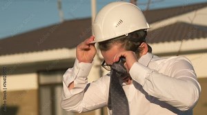 Upset employee architectural engineer takes off his safety helmet and tie while leaving the construction site.