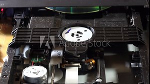 An open DVD player shows its internal components and circuitry, with the disc loading and unloading movements, seen from several angles. This image highlights the technology and design of home enterta