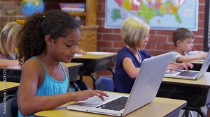 Elementary school students work on laptop computers