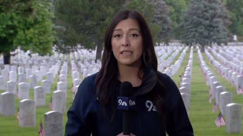 Volunteers place flags on graves at Fort Logan Cemetery for Memorial Day