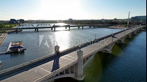 Tempe Bridge over Salt River and Tempe Town Lake in Tempe, Arizona. Aerial shot of bridge and traffic during bright sunset in AZ reflected by water.