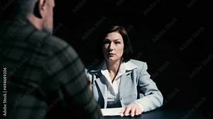 Female police detective questioning male suspect in custody, interrogation room