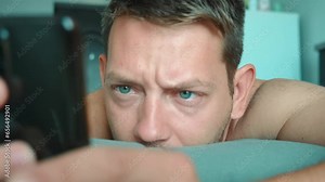 Concentrated man scrolling smartphone in bed in the morning surfing internet, checking social media and reading news. Serious male using mobile phone. Shift focus Stock Video