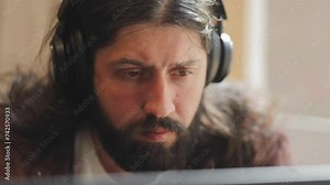 Attractive, bearded, successful man, businessman in headphones focused on work, searching the web, working on a laptop, concentration, studying, freelancer, portrait, video call, programming, IT field