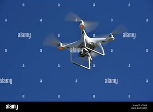 A view from below of a flying DJI Phantom 4 Drone  with a gimbal and camera attached.  Drone, photography, video, flying, surveillance Stock Photo - Alamy