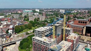 Aerial footage of the city centre of Leeds in the UK showing construction work being done with two large cranes at the Quarry Hill site in the summer time