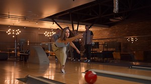 Premium stock video - A woman makes a throw in a bowling club and enjoys emotionally knocking out pins with a ball