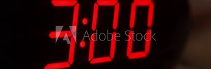 Close-up of black digital clock screen showing 3.00. Blinking red digital numbers on black background. Modern timer system and neon light, electric alarm device