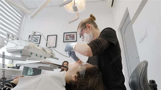 Female dentist treats patient tooth using high speed dental drill and mirror in modern clinic. Doctor performs oral cavity care stomatology procedure treating caries disease maintaining health