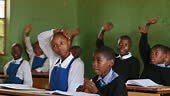 African learners eager to answer question in classroom with hands...