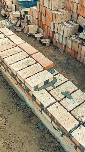 building a high wall using many red bricks and wet cement mortar during outdoor construction work