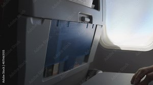 Plane tray table. Opening and closing. passenger's hand opening the tray table on an airplane. air travel experiences. Having a meal on a flight. Dinner lunch or breakfast.