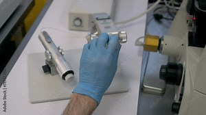 Medical professional operating the modern microscope for diagnostic procedure. Medical doctor with a diagnostic microscope looks at the samples. Medical diagnostic microscope inspecting the embryo.