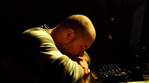 A man is tired in front of a computer in the dark. Burnout concept, unwillingness to work.