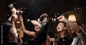 Group of multiracial friends having a christmas party. People sitting at dinner table, holding burning sparklers, drinking wine and smiling - celebration, holidays 4k footage