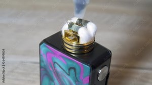Pouring e-liquid juice on clapton coils with cotton stripes in rebuildable dripping atomizer or RDA for vaping. Vaping device for quit smoking. 4K macro video with selective focus.