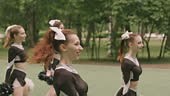 Group of young cheerleaders in sports uniform dancing with pom-poms...