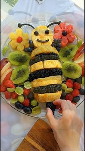 A vibrant fruit platter arranged into a cheerful bee, surrounded by colorful fresh fruit and flower shapes. Bright yellows, greens, and reds create a display that feels lively, balanced, and inviting. Perfect for parties, brunch tables, or any gathering where fruit is meant to be both refreshing and fun to look at. Sometimes a little creativity is all it takes to turn a fruit tray into the centerpiece. | Kitchen plate