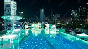 Nighttime rooftop pool with holographic displays. Floating platforms and bioluminescent drinks create surreal atmosphere. Partygoers mingle amidst dynamic light patterns.