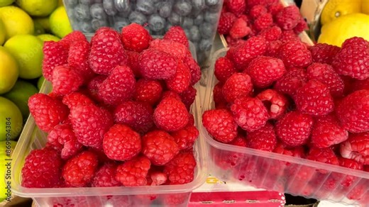 Raspberries and blueberries in containers. Foodstuffs and fruits. Harvest and market. Healthy eating.
