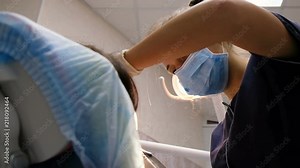 Young woman dentist is treating and drilling teeth to a patient. On reception at the doctor of the stomatologist