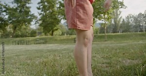 A young woman practices modern dance moves in a city park, her bare feet moving gracefully across the grass. She rehearses her performance on a sunny day.