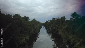 From the top view of an indigenous person paddling a canoe in a rainforest river