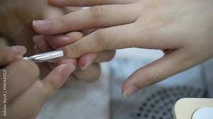 the hands of a professional salon worker holding a client's hand while using a cuticle pusher. Manicurist using cuticle pusher on girl's hands. Manicurist makes a manicure in a nail salon.