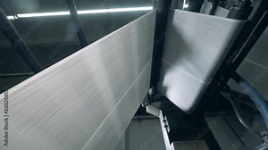 A loom weaving threads, working automatically at a factory.