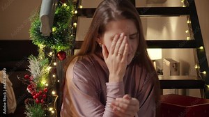Young upset woman crying on wooden stairs being left alone on Christmas. Negative emotions, depression and solitude on celebrations