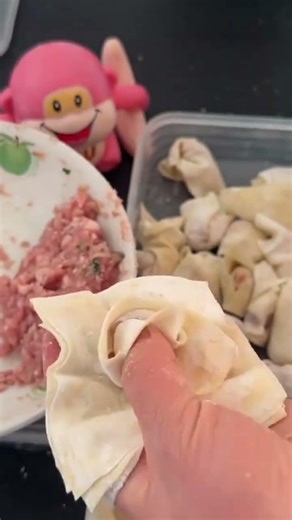 A person is wrapping spring roll pastry around fingers while preparing filled #construction #popular