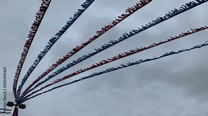 Streamers over a parking lot in severe wind. Storm wind, hurricane wind with red and blew tinsel attached to parking lot street light