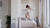 happy woman jumping on bed in hotel room having fun enjoying vacation...
