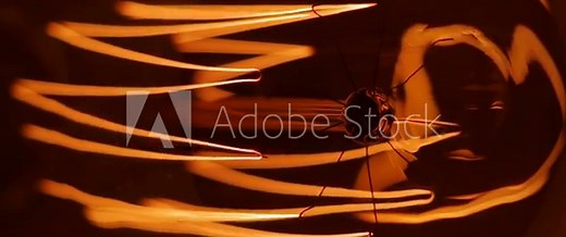 Close-up on a vintage Edison light bulb turning on and off. Filmed in a dark environment.