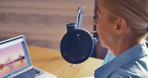 Download The podcast host in his home studio is animatedly communicating with the podcast participants. there is a computer and notepads on the table for free