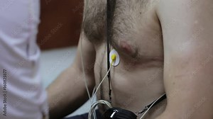 Female doctor attaching electrodes on patient's chest to daily monitoring
