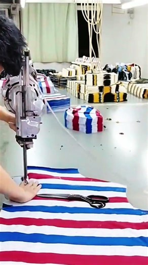 Large scissors rest on striped fabric in busy workshop