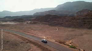 A parallel drone shot following a driving car in the desert, filmed in Timna Nature Park, Israel.