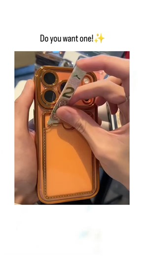 ExploreRee.Io™ on Instagram: "The post features a short video demonstrating an orange iPhone case with integrated wallet slots, where Indonesian Rupiah banknotes (dated 2020-2026) are inserted, promoting it as a convenient and stylish accessory via the caption "Do you want one!". Posted on January 19, 2026, by @softy_queen05 , a creator known for aesthetic lifestyle content, it garnered over 17,000 likes and 11 million views in under 48 hours, reflecting strong interest in functional tech-fashio