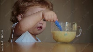 Baby eats soup with a spoon. Child have a meal. Hungry little kid eating kids food. Baby porridge. Little baby eating healthy food. A Little baby eating her dinner. Close-up portrait of kid with food.