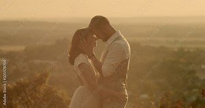 Bride and groom embracing in rural setting. Loving bride and groom standing face to face in sunlit countryside. Real-time, hand-held shot, medium shot, 4K.