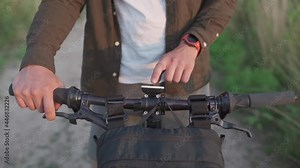 Cyclist use bicycle computer on handlebars of mountain bike in nature. Traveler on cycle looks at map, builds route using GPS on bicycle navigator. Activity tracker and offline maps for bike rides.