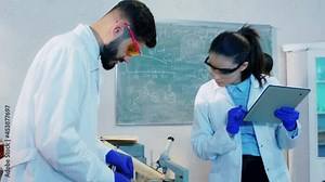 Biotechnology laboratory group of pharmacist working together make experiments mixed the chemical substance into the glass tube and write the results on the digital tablet