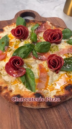 CHARCUTERIE PIZZA! This is how to turn your charcuterie board into a meal! Full recipe below! Makes one 12-inch pizza pie Ingredients: ⅓ cup olive oil 6 garlic cloves minced ½ tsp salt 1, 10-ounce pizza dough 4 ounces fresh mozzarella ¼ cup grated parmigiano Reggiano 6 pepperoncini, chopped 16 slices of salami 3 slices prosciutto 10-12 basil leaves Oven Instructions: Place your pizza stone on the middle rack of your oven. If you do not have a pizza stone, take your largest baking tray and place 