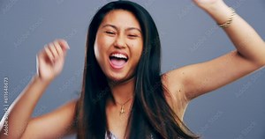 Excited, dance and face of Asian woman singing in studio isolated on gray background. Dancing, singer and female person moving, freedom or good news celebration, portrait and dancer at music party.
