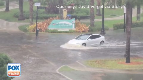 A Tesla driver takes a risk by driving through the heavy flood waters in Sunny Isles Beach, Florida.