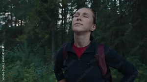 Portrait of the female hiker in the forest. Relaxed woman hiker stands in the forest