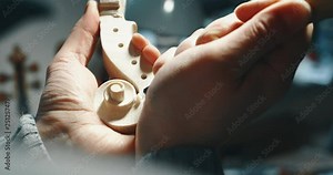 Slow motion close up of master artisan luthier painstaking detailed work on wood violin in a workshop. Shot in 8K. Concept of spiritual instrument, handmade, art, orchestra, artisan, passion for music