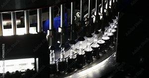 Close up of ampoule production machine. ampoules manufacturing a lot of injections in glass ampoule vial in a healthcare pharmaceutical factory making process blue light with latest hi tech machinery